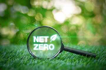 Magnifying glass focused on net zero text on grass in garden with green nature background for choosing Eco-friendly environmental, energy-saving. carbon neutral .A climate-neutral long-term strategy.
