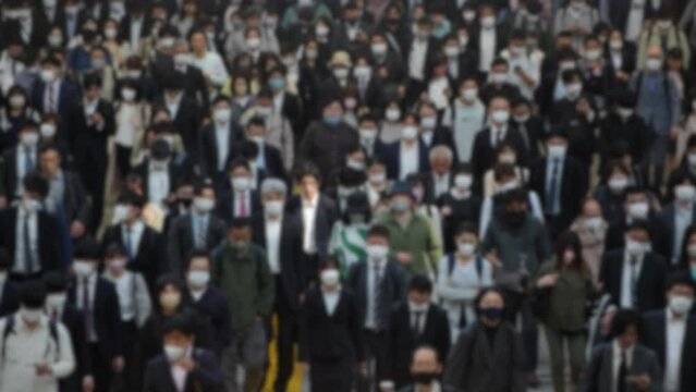 Blurred defocused view of from above, a sea of people moving in unison, with hardly any space between them. This is the daily scene in Tokyo, where the city's density is on full display