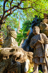 Within the historic confines of a Bangkok temple, sculptures and lush plants converge to form an enchanting scene.