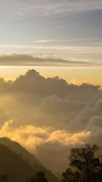 Vertical video - Timelapse of the sun setting over layers of rolling clouds on the mountain, taken in Mount Bromo, Indonesia