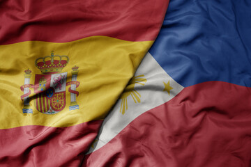 big waving national colorful flag of spain and national flag of philippines .