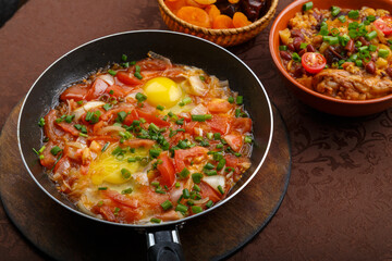 hot shakshuka in a frying pan sprinkled with green onions on the Shabbat table.