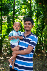 South asian young man with his little baby boy in a outdoor park 