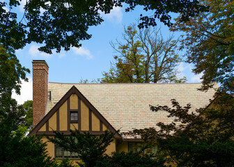 Fototapeta na wymiar Old house roof framed by foliage with blue sky background, Boston, Ma, USA