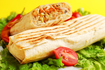 Tasty shawarma with lettuce and tomatoes on yellow background