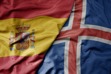 big waving national colorful flag of spain and national flag of iceland .