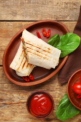 Plate with tasty shawarma and ketchup on wooden background