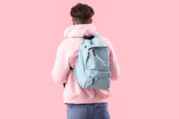 Male student with backpack on pink background, back view