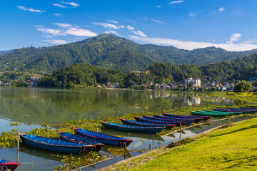 Fototapeta na wymiar Beautiful Green Phewa Lake with Boats and Green Mountains in Pokhara City of Nepal during monsoon