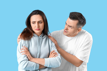 Fototapeta premium Offended young woman with her husband on blue background