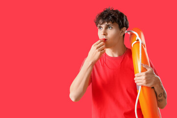 Male lifeguard with ring buoy whistling on red background