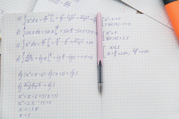 Open copybook with math formulas and pen as background, closeup