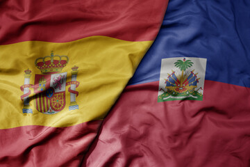 big waving national colorful flag of spain and national flag of haiti .