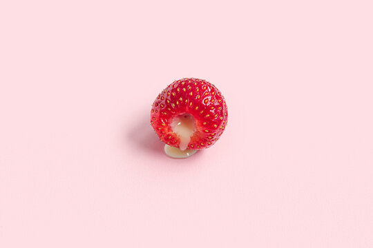 Fresh strawberry with liquid on pink background. closeup. Sex education concept