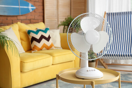 Electric fan on wooden coffee table in interior of stylish living room