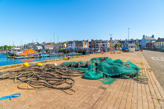 A fishing net and rope lies along the docks at the fishing pier, with the Scottish town of Stornoway behind on Lewis and Harris Island, Stornoway, Scotland.
