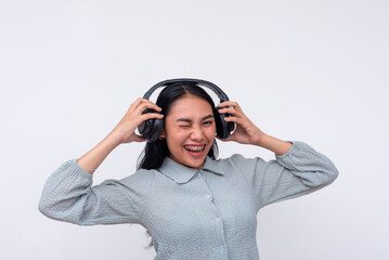 A young asian woman winks while listening to great music on her wireless headphones. Isolated on a white background.