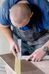 Professional tiler measuring and sticking with tape for cutting ceramic tiles for installing floor. Construction, renovation, repair apartment.