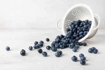 Colander with fresh blueberries on white background