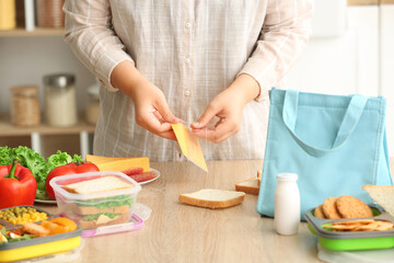 Mother making sandwiches for school lunch on table at kitchen