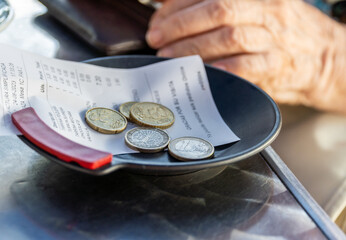  A person picks up some euro coins on a plate with the restaurant bill receipt