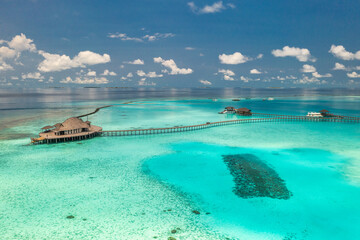 Aerial landscape of Maldives island, luxury water villas resort and wooden pier. Beautiful sky sea...