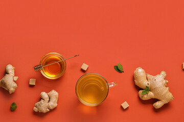 Glass cup of ginger tea and bowl with honey on red background
