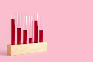 Test tubes with samples in wooden stand on pink background