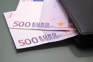 Five hundred euro bills, banknotes inside a wallet, close-up on dark background. Cash money
