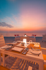 Stunning romantic dinner on sunset beach candles under colorful sea sky. Romance and love, luxury destination dinning, exotic table setup with sea view. Couples celebration honeymoon or anniversary