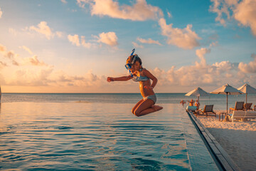 Amazing sunset sea sky with joyful girl in snorkel gear jumping into pool. Tropical resort beach umbrellas, infinity poolside Excited funny little girl jumping to swimming pool. Happy summer vacation - 639373515