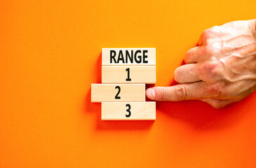 Time to range 2 symbol. Concept word Range 1 2 3 on wooden block. Businessman hand. Beautiful orange table orange background. Business planning and time to range 2 concept. Copy space.