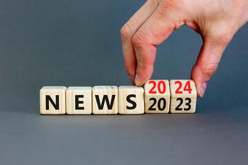 2024 News new year symbol. Businessman turns a wooden cube and changes words News 2023 to News 2024. Beautiful grey table grey background, copy space. Business 2024 news new year concept.