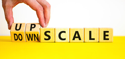 Upscale or downscale symbol. Concept words Upscale or Downscale on wooden cubes. Beautiful yellow table white background. Businessman hand. Business upscale or downscale concept. Copy space.