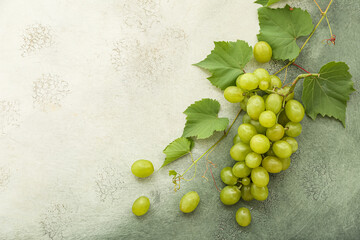 Sweet green grapes with leaves on grunge background