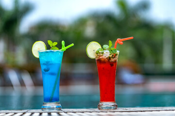 Summer Vacation Concept : Welcome drink juice punch put on poolside nearly swimming pool with blue water. Fresh alcoholic red and blue cocktail