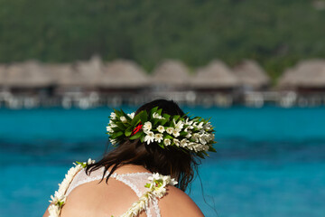 Femme brune en robe de mariée et couronne de fleurs sr la plage en Polynésie 