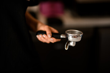 Fototapeta na wymiar Professional holder for ground coffee in female hand. Tools for preparing coffee in coffehouse or restaraunt.