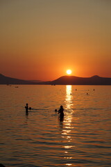 Lake Balaton at sunset with people silhouette and the north part mountains in the background