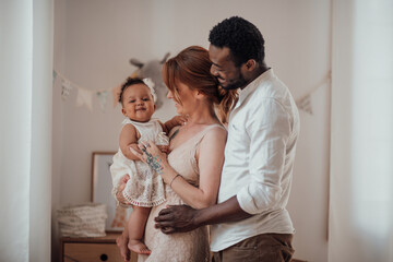 Portrait of candid friendly happy interracial family with swarthy baby together at children room