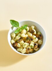 Potato gnocchi with mushroom, parmesan cheese and greens in bowl over light background with free space.