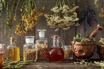 Bottles of tinctures and oils with dry herbs in a pantry - obrazy, fototapety, plakaty