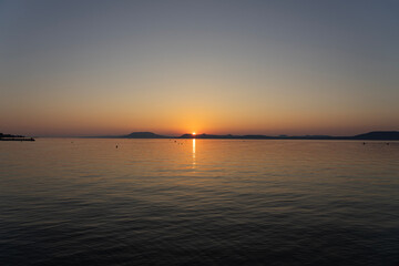 sunset at Lake Balaton with silhouette of night bathing people and the north part mountains in the background