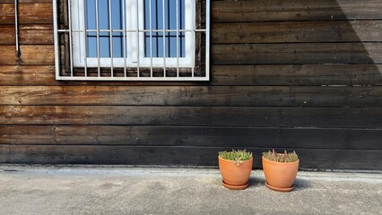wooden house, flowerpots, window with bars