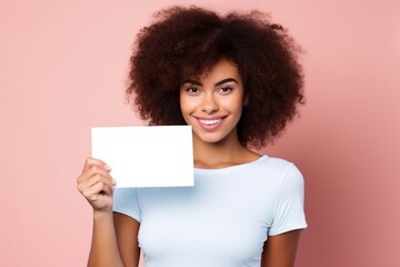 female wearing white tshirt holding up blank card for mock ups on pink background