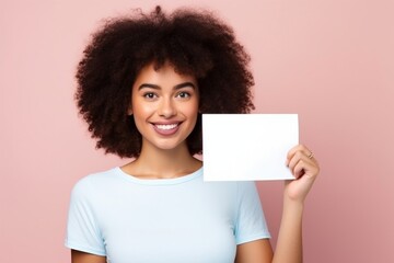 female wearing white tshirt holding up blank card for mock ups on peach background
