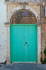 Traditional old wooden door of light green color at an old house with stone arch and iron lintel, in Preveza town, Epirus region, Greece, Europe