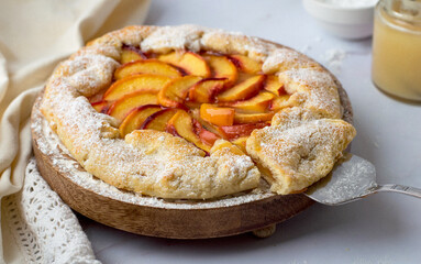 Biscuit with peaches on a stand sprinkled with powdered sugar and poured with honey. Close, horizontal..
