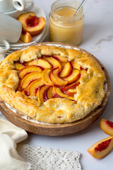Biscuit with peaches on a stand, a jar of honey, saucers and cups for tea drinking. Getting ready for a tea party with a pie..