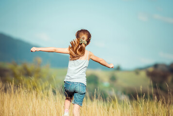 little girl runs through a beautiful meadow in the mountains. back view